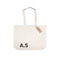 Beige tote bag with 'A.S.' initials and a tag on a white background