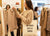 Four colorful tote bags (yellow, red, blue, orange) hanging on a rack against a white wall.