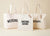 Four colorful tote bags (yellow, red, blue, orange) hanging on a rack against a white wall.
